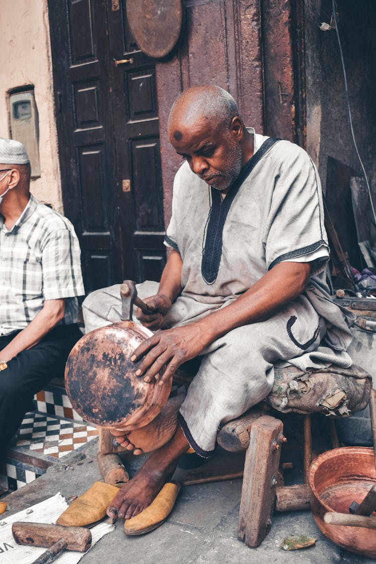 Elderly Man Hammering Round Container