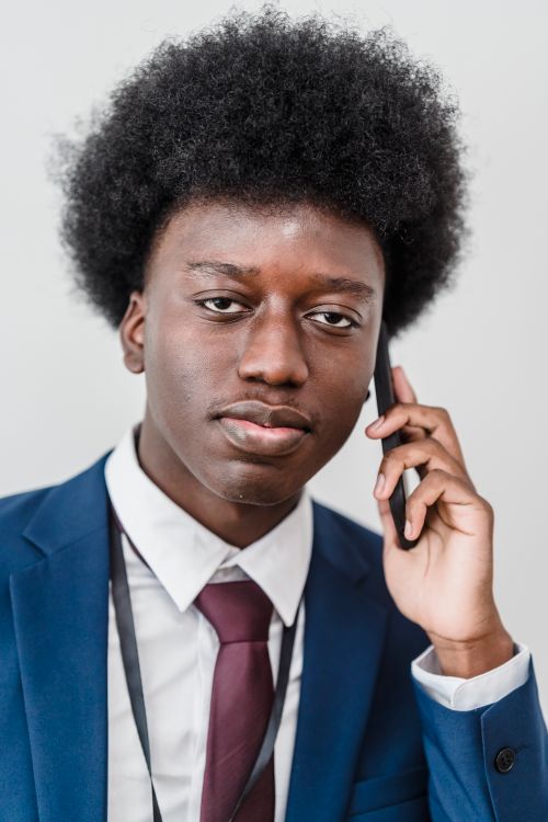Free Portrait of a confident businessman using a phone, wearing a blue suit and white shirt. Stock Photo