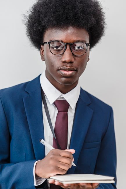 African American businessman in a suit writing notes in a notebook indoors. African American businessman in a suit writing notes in a notebook indoors.