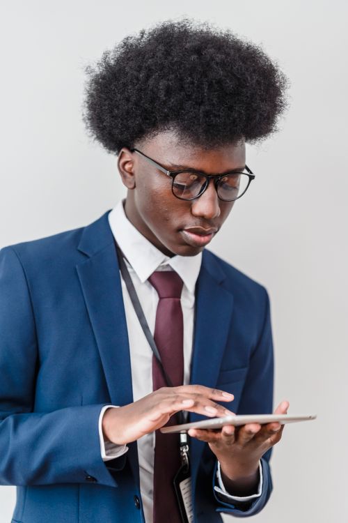 Free Young black man in business suit using a tablet, showing focus and sophistication. Stock Photo
