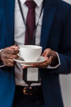 Close-up of a businessman in a suit holding a coffee cup, showcasing elegance and lifestyle.