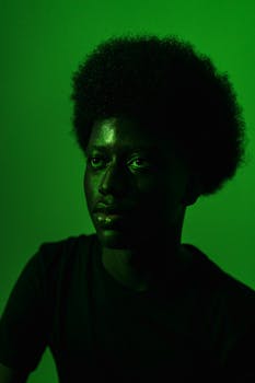 Striking portrait of a man with afro against a vivid green background.