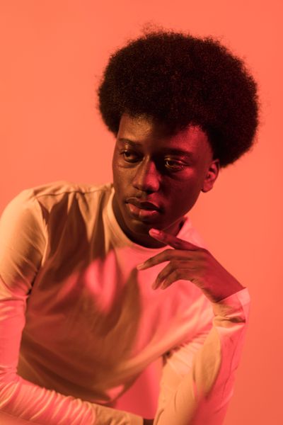Studio portrait in coral light — Lara Jameson on Pexels