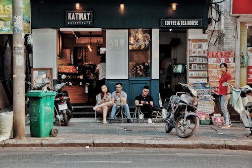 免费 三人坐在摩托车旁的咖啡和茶馆外的椅子上 素材图片