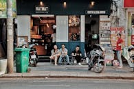 人们坐在城市街头的咖啡店外，喝着饮料聊天