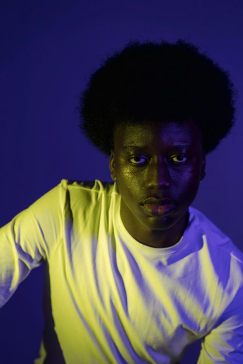 Free Vibrant portrait of a man in studio lighting with contrasting blue and yellow tones. Stock Photo
