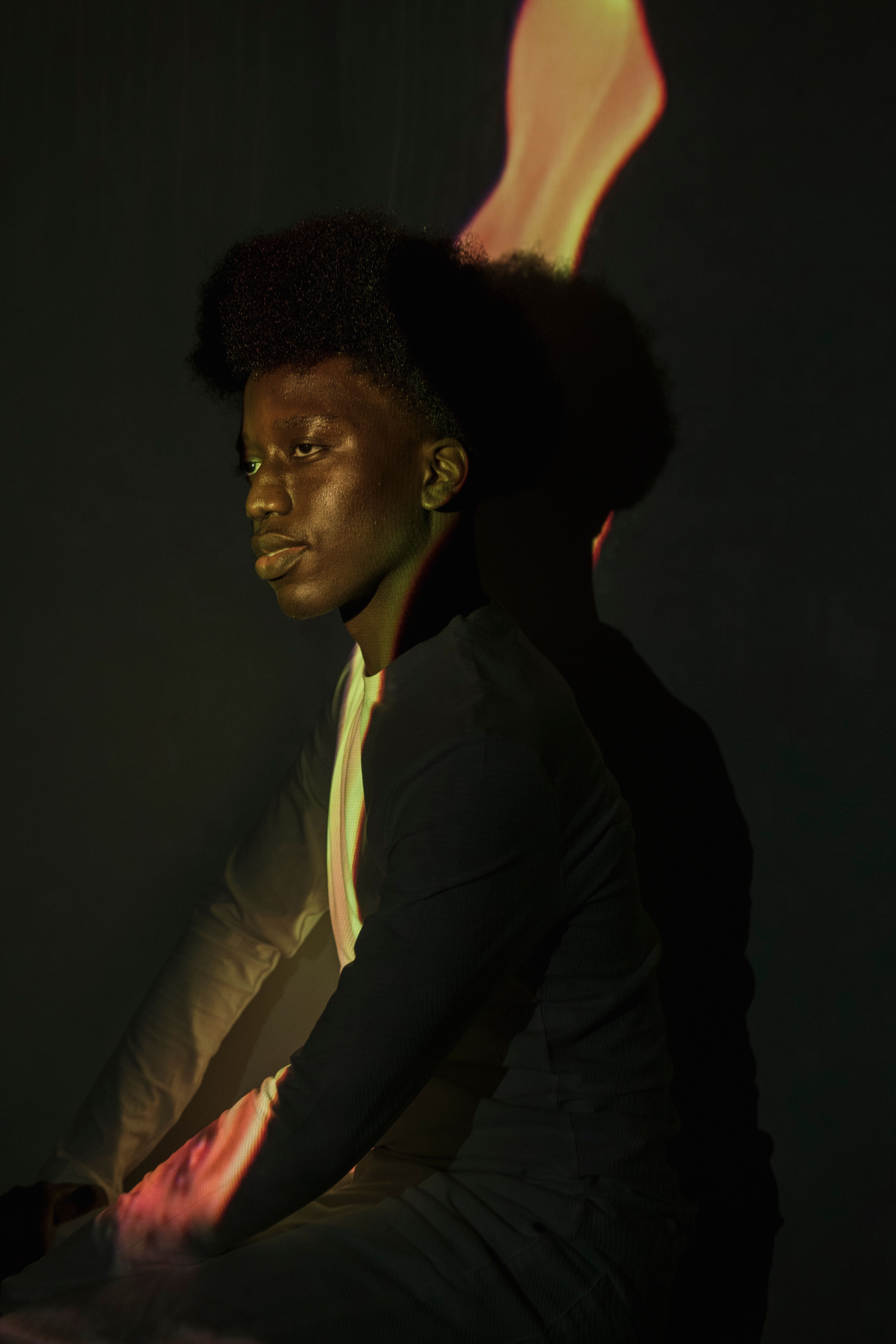 Creative studio portrait featuring a man with projected light patterns and a dramatic pose.