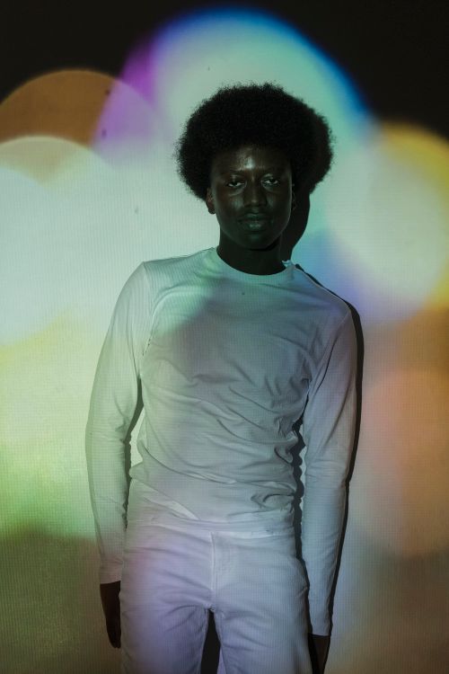 Free Artistic portrait of a man with vibrant light patterns projected on him in a studio setting. Stock Photo