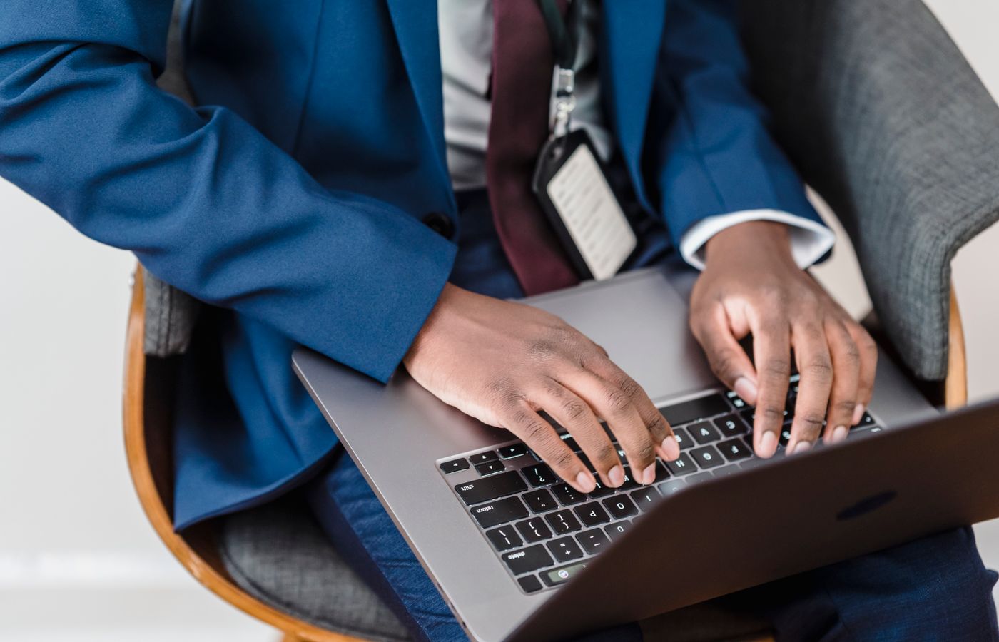 Close-up of a businessman in a blue suit working on a laptop indoors.