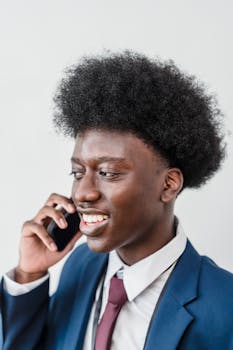 A smiling African American businessman in a suit talks on his mobile phone.