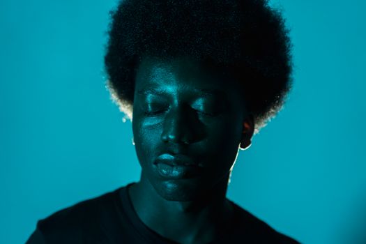 Close-up of an African American man with afro hair against a blue background.