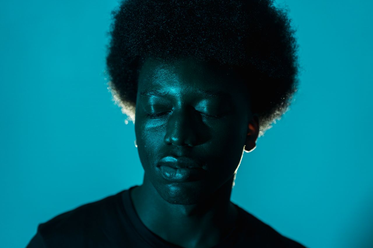 close up of an african american man with afro hair against a blue back