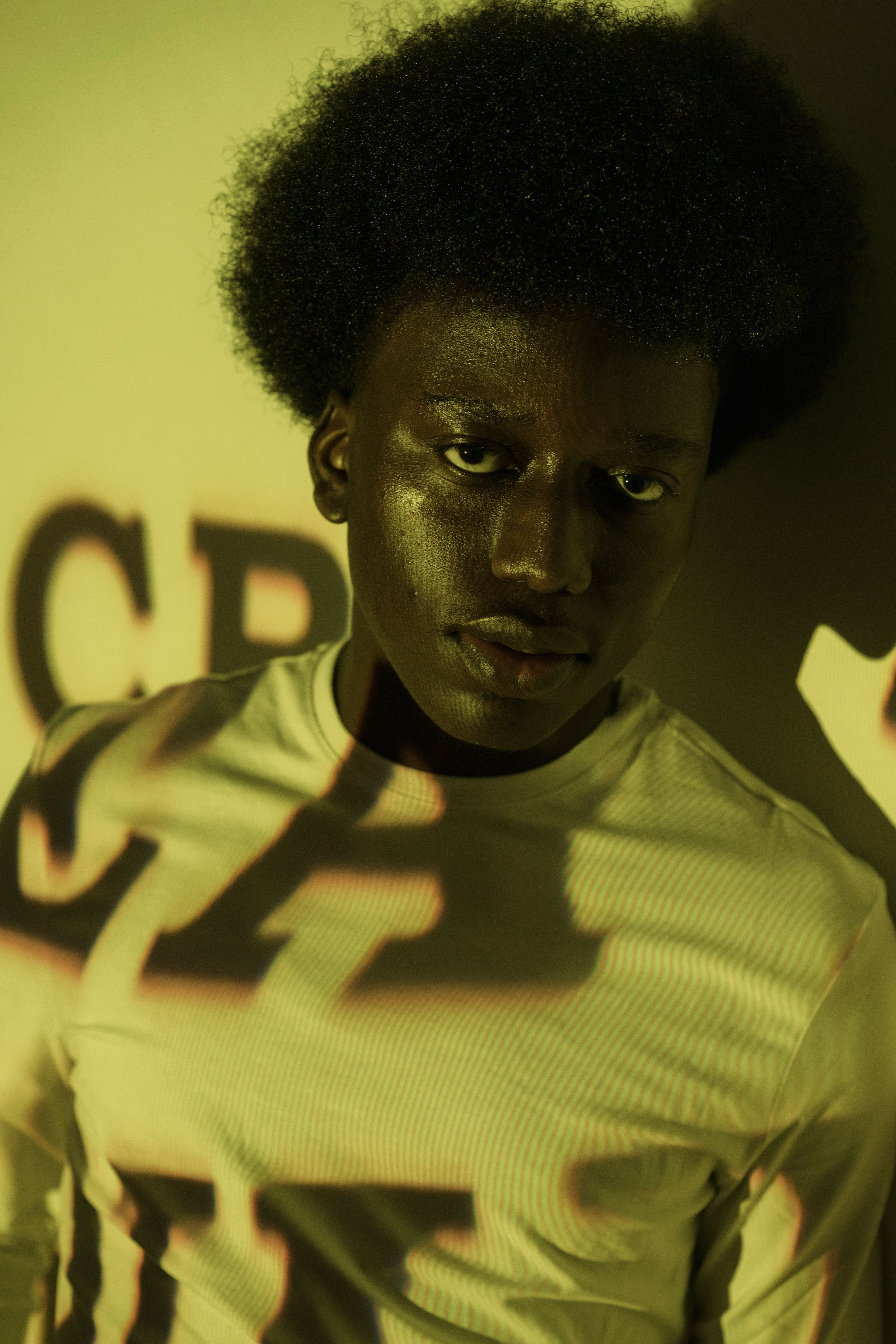 Artistic portrait of a man with projected letters creating a dynamic shadow effect.