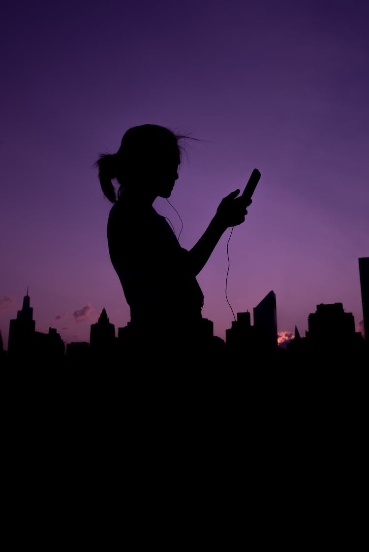 A Silhouette Of A Person Holding A Cellphone