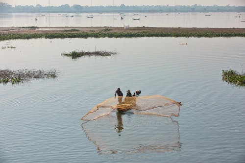 Aerial View of Men Throwing a Fishing Net while Sitting in a Boat