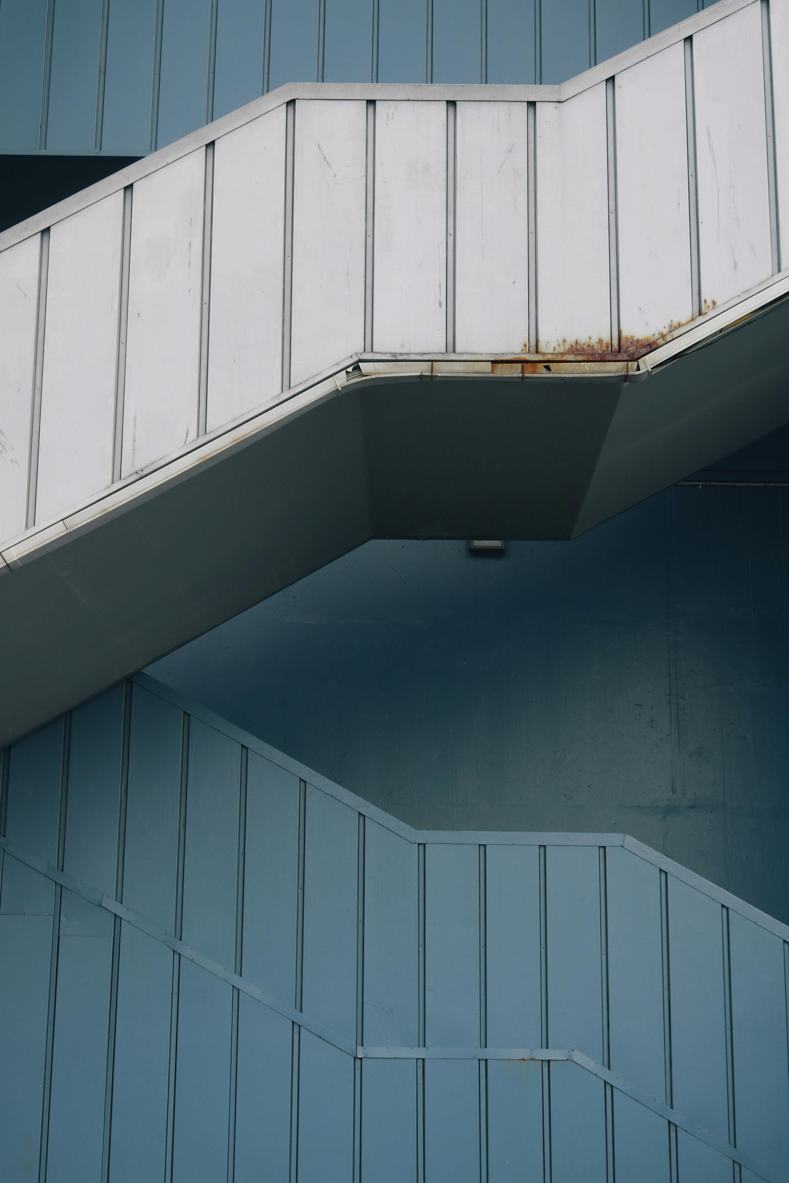 Vertical shot of a minimalist white and blue staircase with geometric lines.