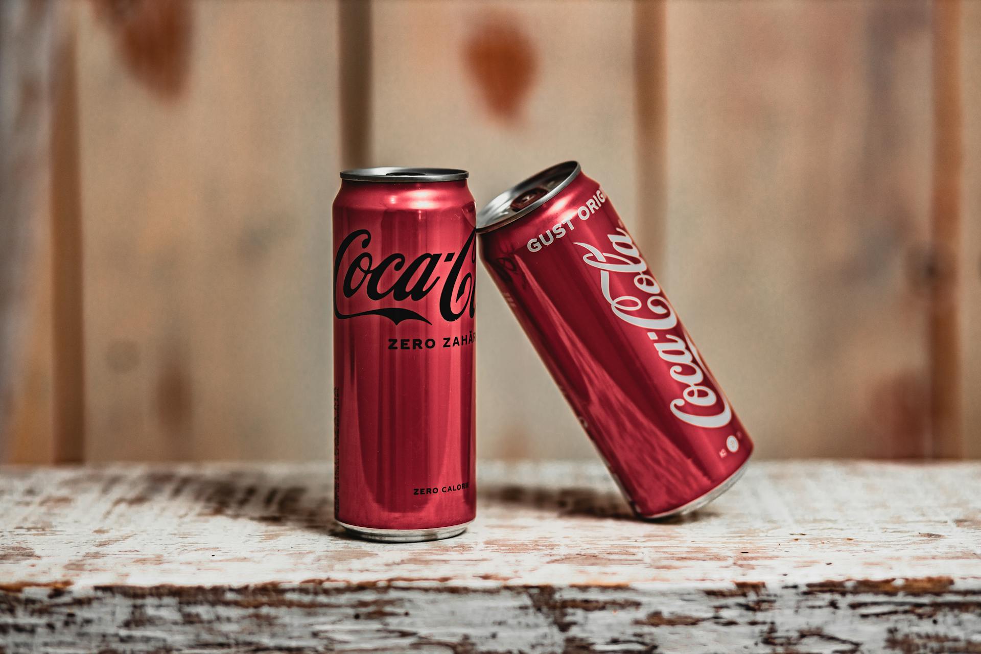 Coca Cola Cans on Brown Wooden Table