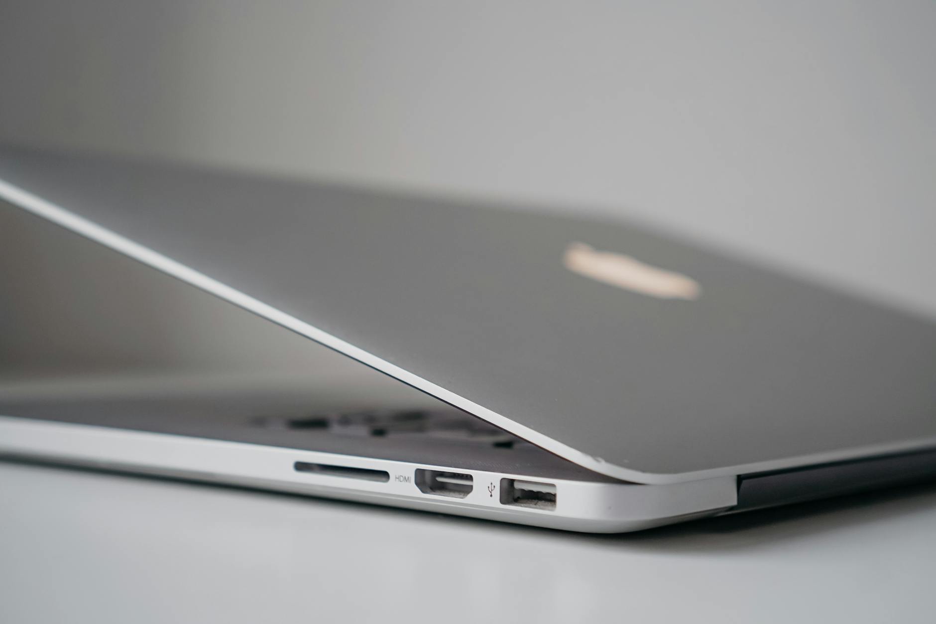 Close-up view of a sleek silver laptop with partially open lid, highlighting ports and sleek design.
