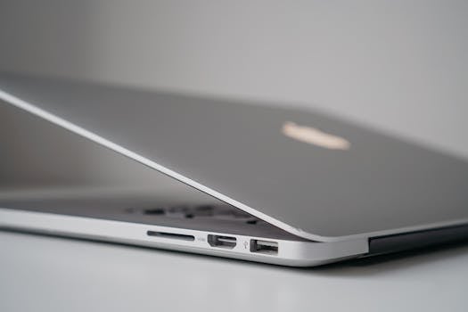 Close-up view of a sleek silver laptop with partially open lid, highlighting ports and sleek design.