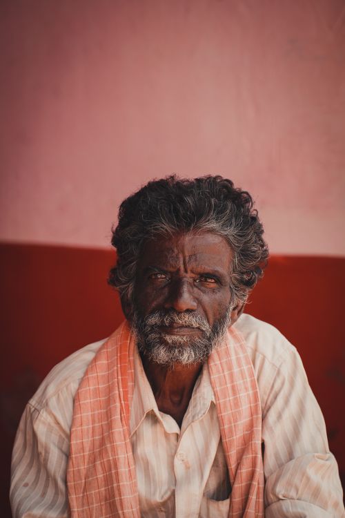Free Close-up portrait of a serious elderly man with a beard, wearing traditional attire indoors. Stock Photo