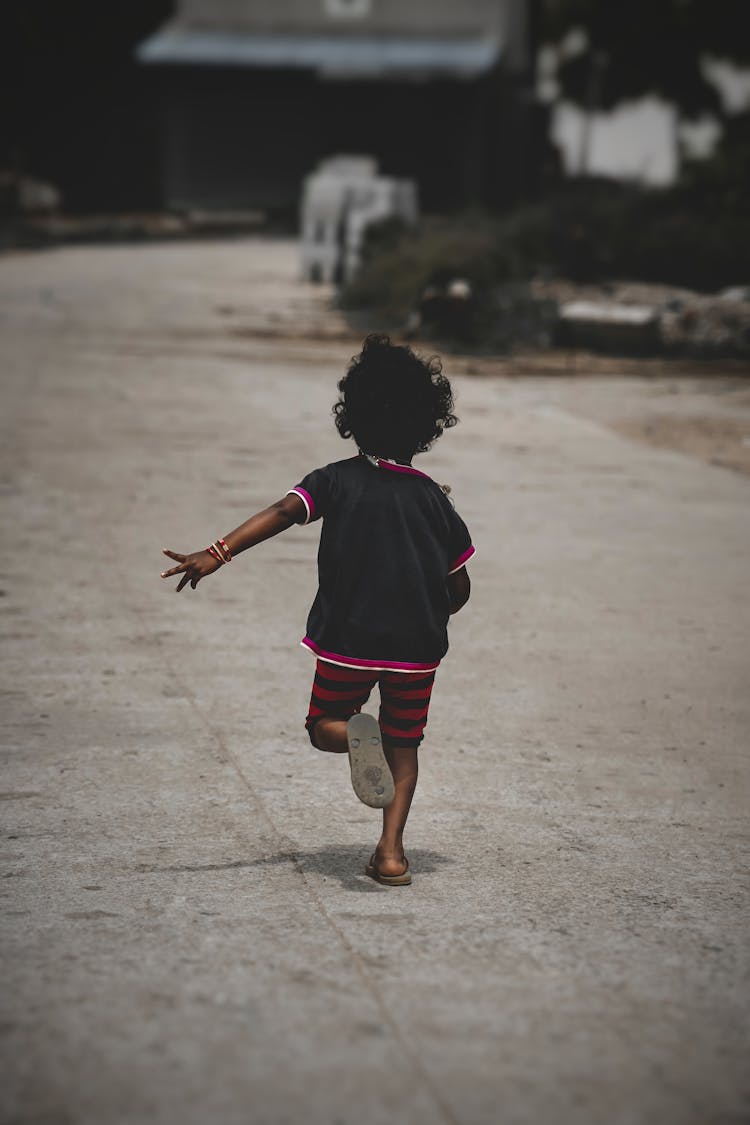 Back View Of A Child Running On Concrete Road