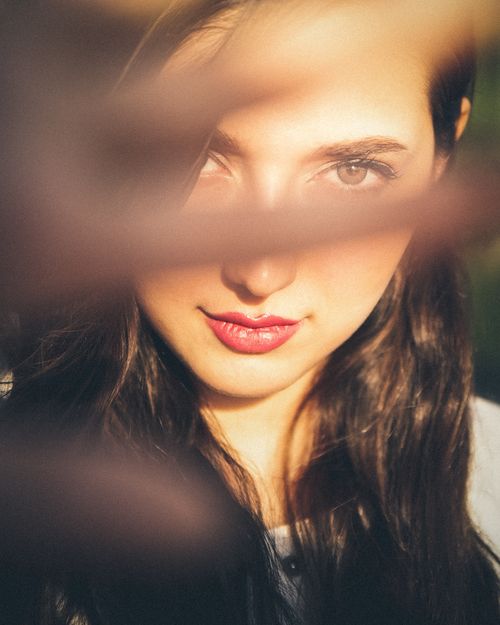 Free A captivating artistic close-up portrait of a woman partially obscured by out-of-focus foreground. Stock Photo