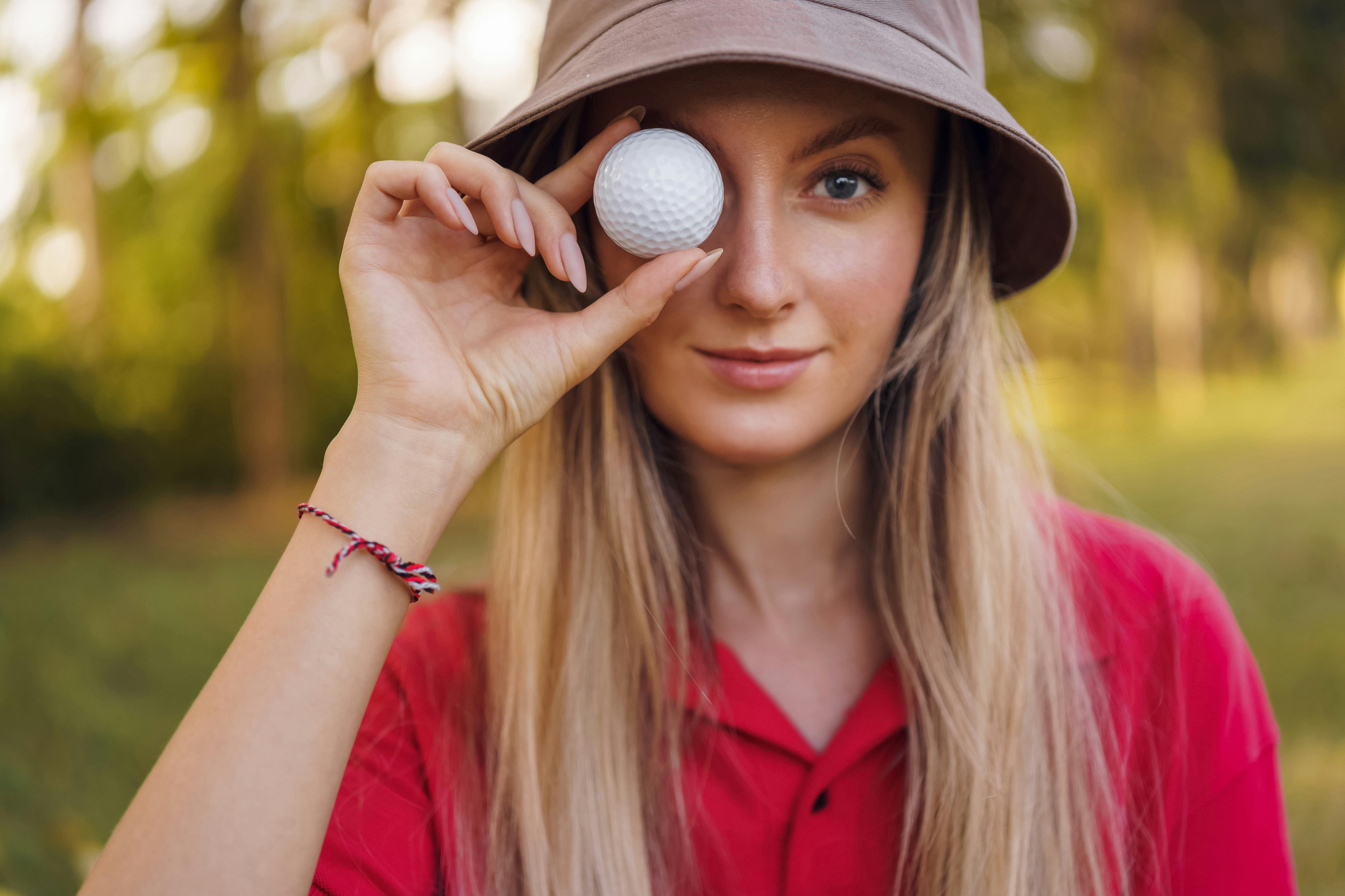 woman holding a golf ball near her eye