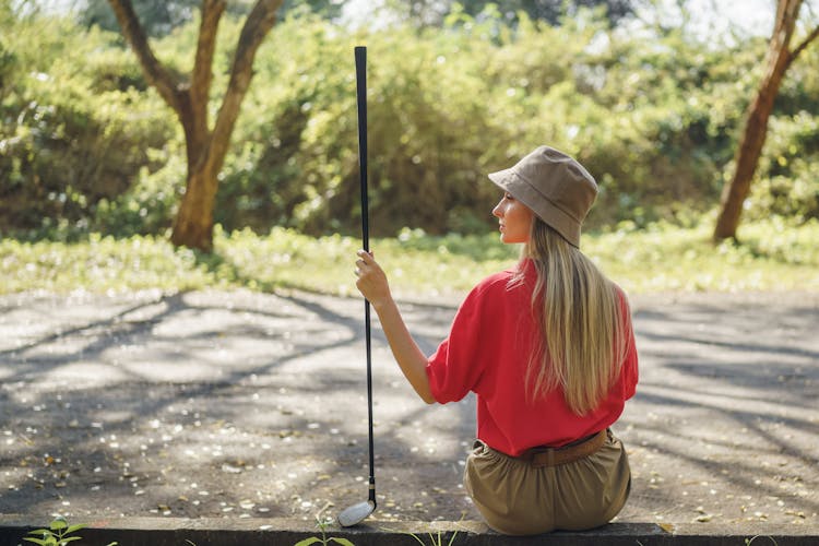 Woman In Red Shirt And Brown Pants Holding Black Golf Club