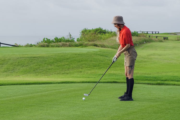 A Woman In Red Polo Shirt Playing Golf