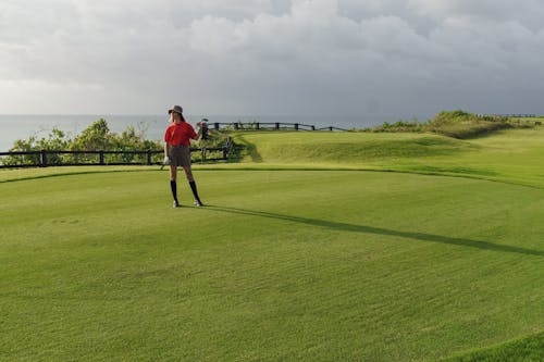 A Woman in Red Polo Standing on the Grass Field