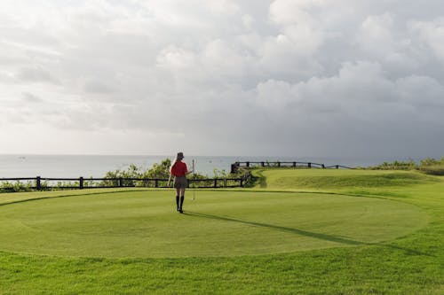 A Woman in Red Polo Shirt Standing on Green Grass Field