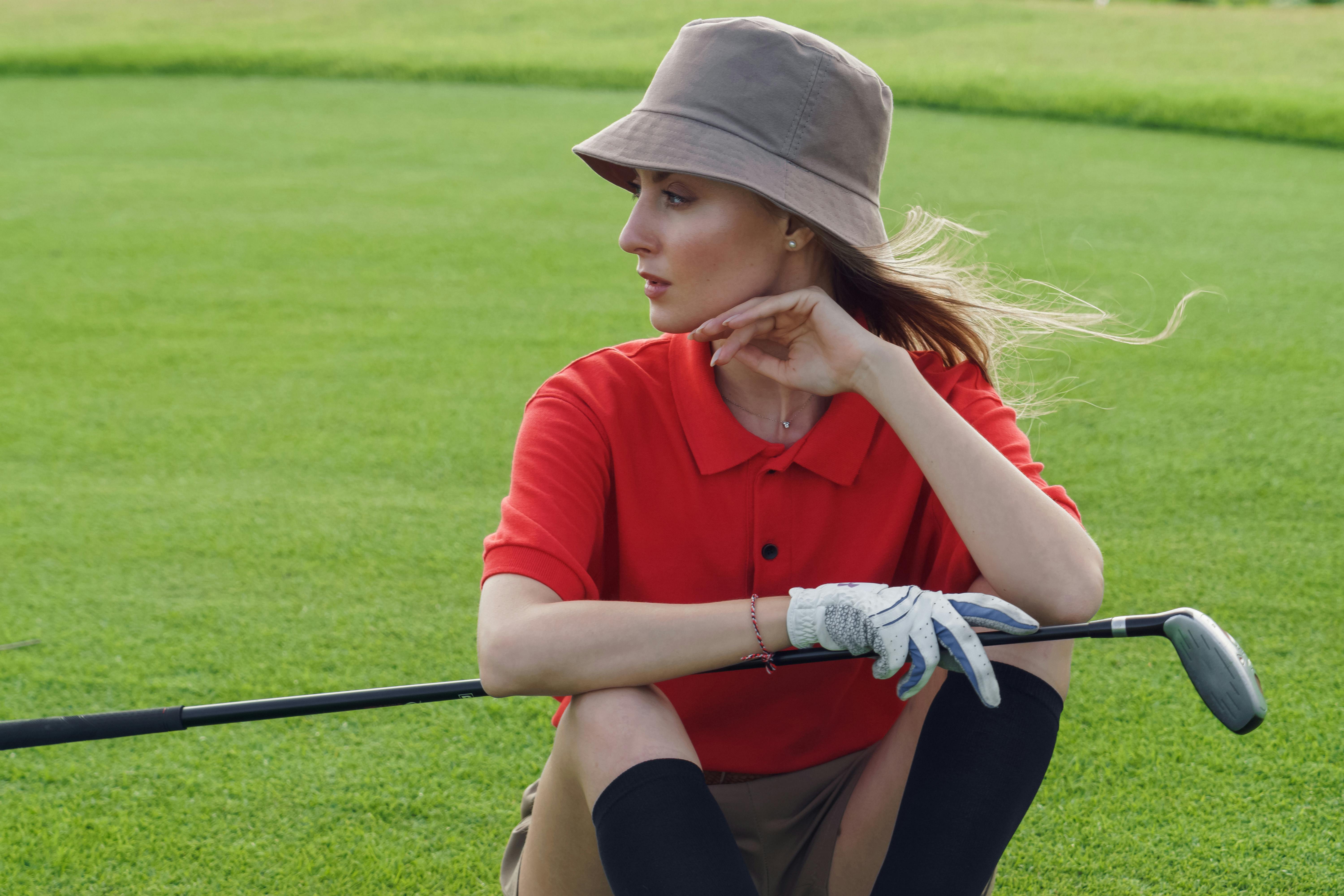 a woman sitting in the golf course holding golf club