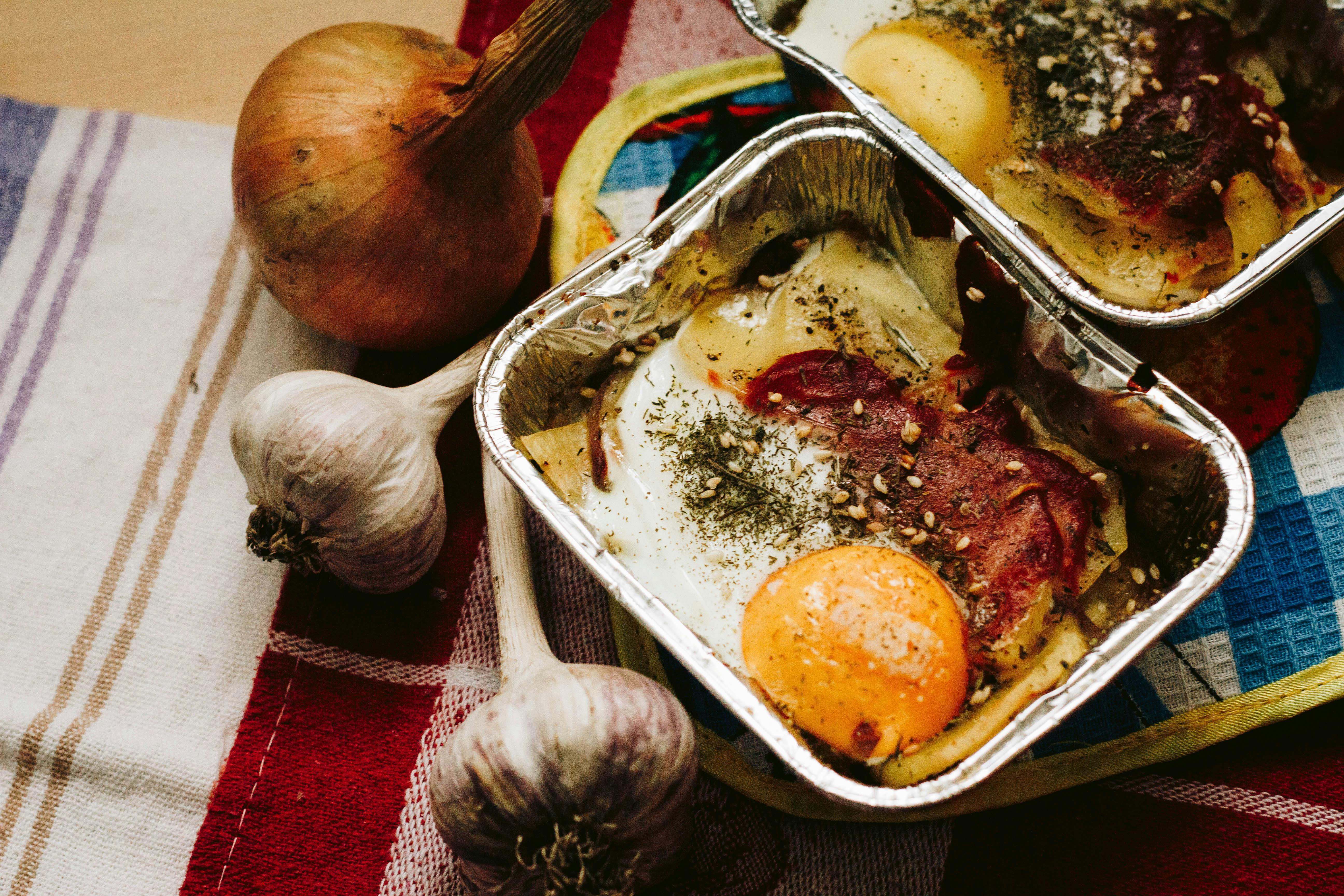 cooked food in square grey tray beside garlics and onion