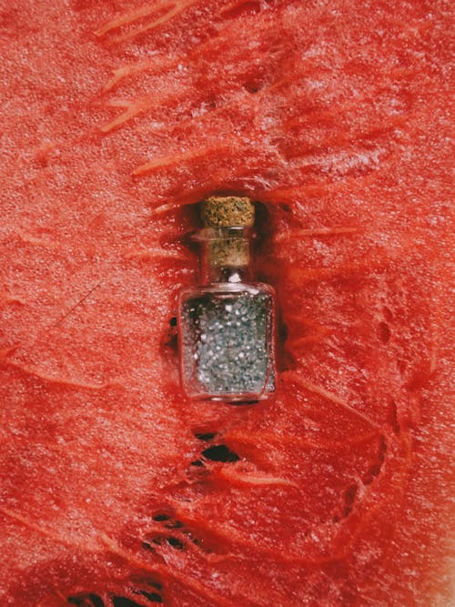 Glass Bottle with Glitters on Red Surface
