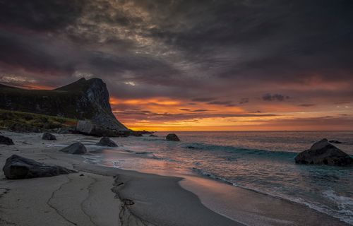 Free Dramatic sunset over Myrland Beach, Norway, with rocky shore and vibrant sky. Stock Photo
