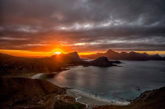 A breathtaking sunset over Nordland, Norway, with dramatic clouds and vivid colors reflecting on the ocean.