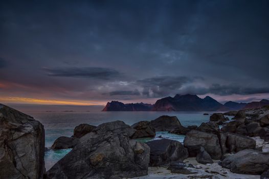 Beautiful scenic view of Myrland's rocky coast at dusk with dark clouds and mountains.