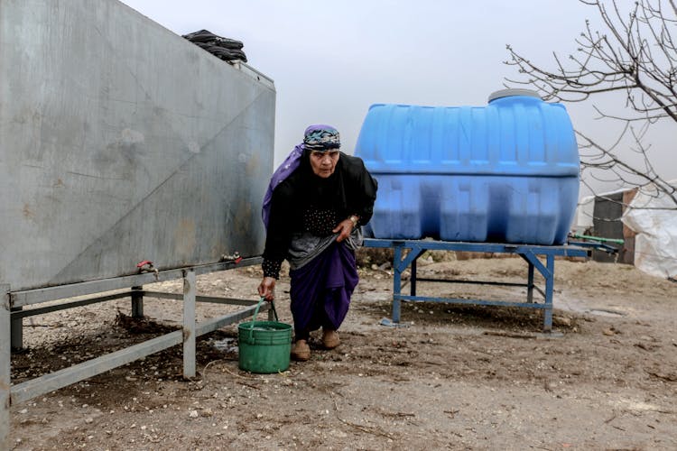 Elderly Woman Carrying A Bucket