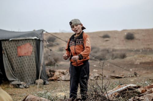 Free Smiling young boy in an orange jacket at a refugee camp in Idlib, Syria Stock Photo