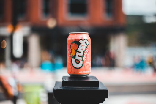 Vibrant close-up of a Crush Peach soda can placed outdoors on a blurred urban background.