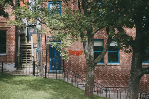Free View of a brick building with blue windows and door, framed by trees. Stock Photo