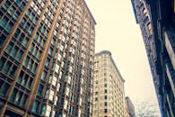 在明亮的天空下，低角度拍摄的高大现代摩天大楼构成了戏剧性的城市景观