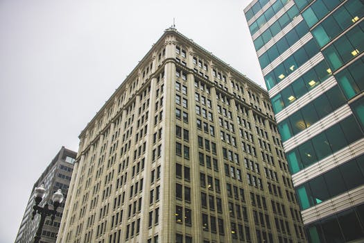 低角度拍摄城市环境中玻璃窗的当代摩天大楼，天空多云呈灰色