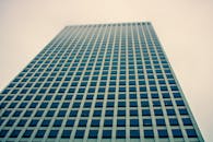 低角度镜头下，阴沉的天空映衬着一座带玻璃窗的现代摩天大楼