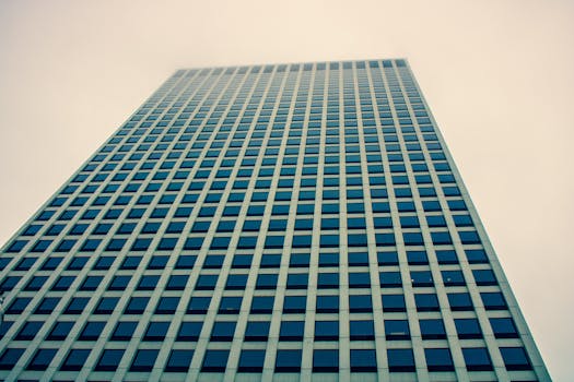 低角度镜头下，阴沉的天空映衬着一座带玻璃窗的现代摩天大楼