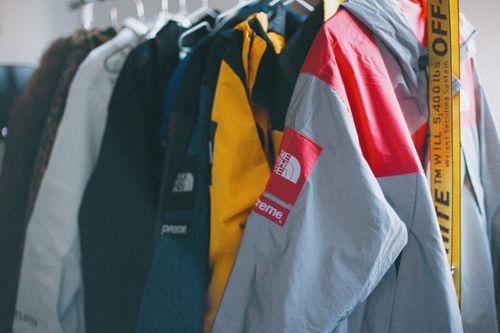 Free A collection of colorful Supreme jackets hanging on a clothing rack indoors. Stock Photo