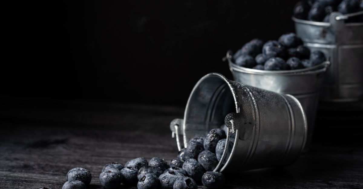 Close-up of fresh blueberries spilling from galvanized metal buckets on a dark surface. - Evidence evidence guide for blueberry sleep quality meta-analysis