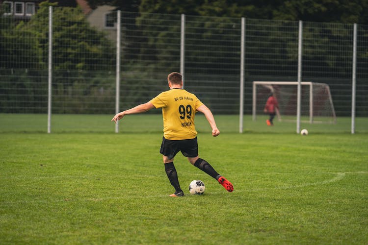 Back View Of A Man Kicking A Soccer Ball