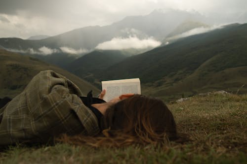 
A Woman Reading a Book while Lying Down on the Grass