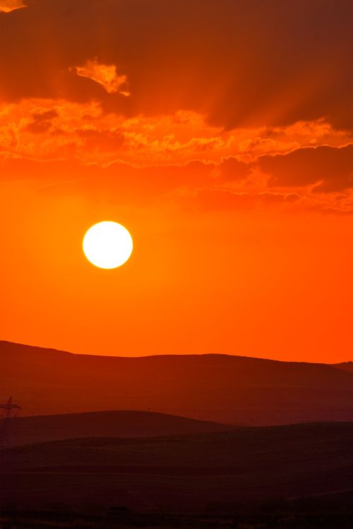 Free A breathtaking sunset with a vibrant orange sky over peaceful hills. Stock Photo